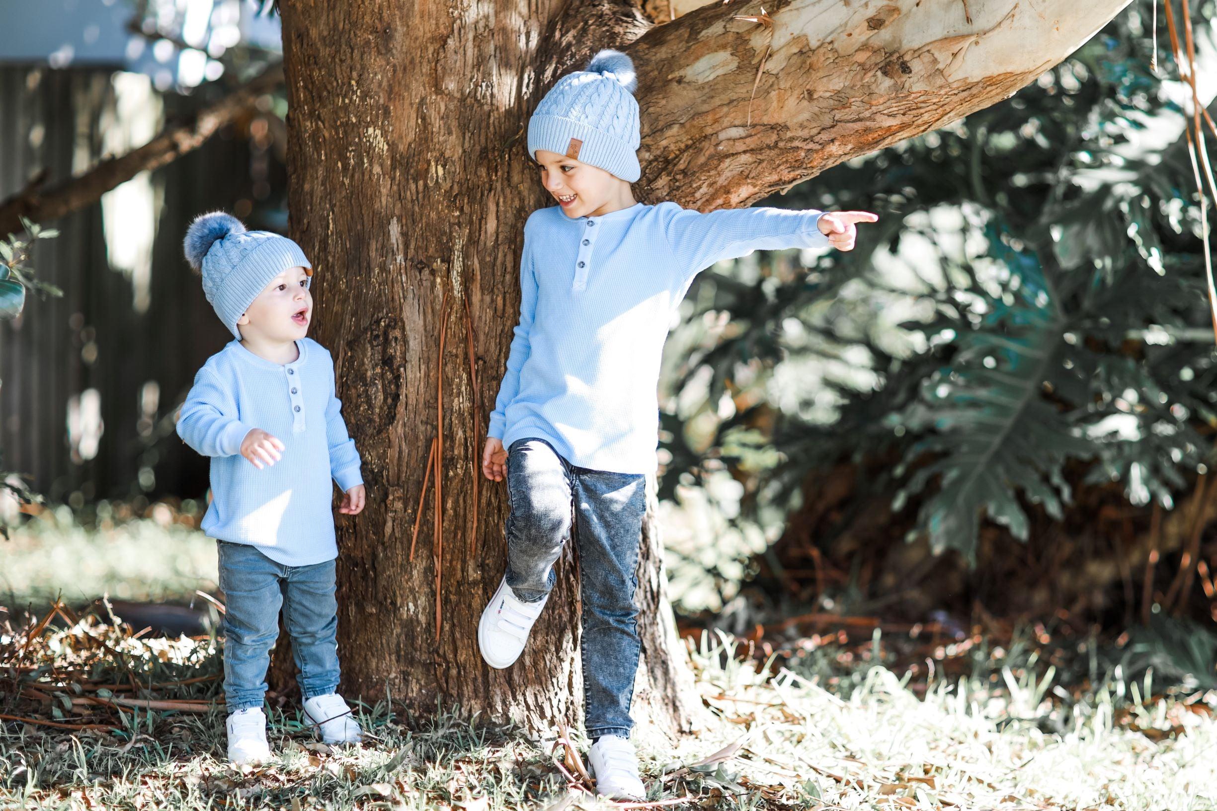 brothers, boys wearing blue winter pom pom beanies in the park
