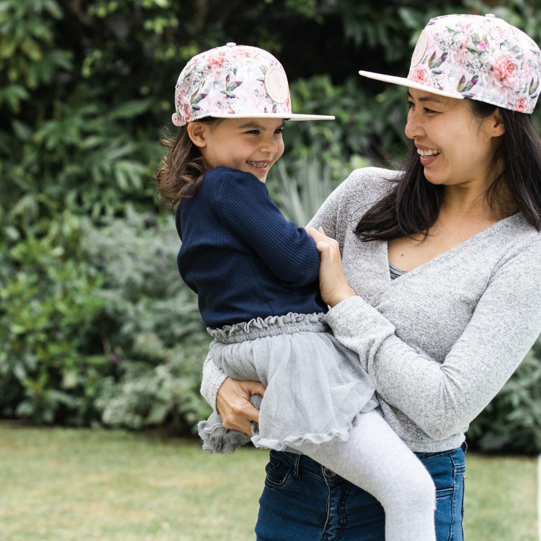 Matching mum and daughter wearing pink floral snapback hats. Cubs & Co. Australia.