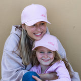 Mum and daughter wearing matching pink baseball caps with Mama and Mini. Cubs & Co. Australia.