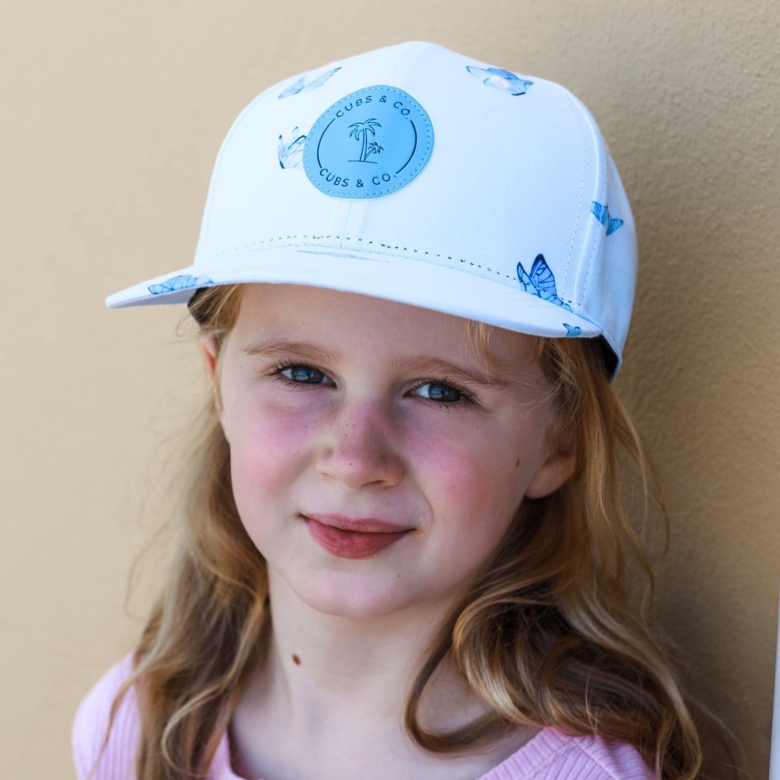 Girl wearing a blue butterfly snapback baseball cap. Cubs & Co. Australia