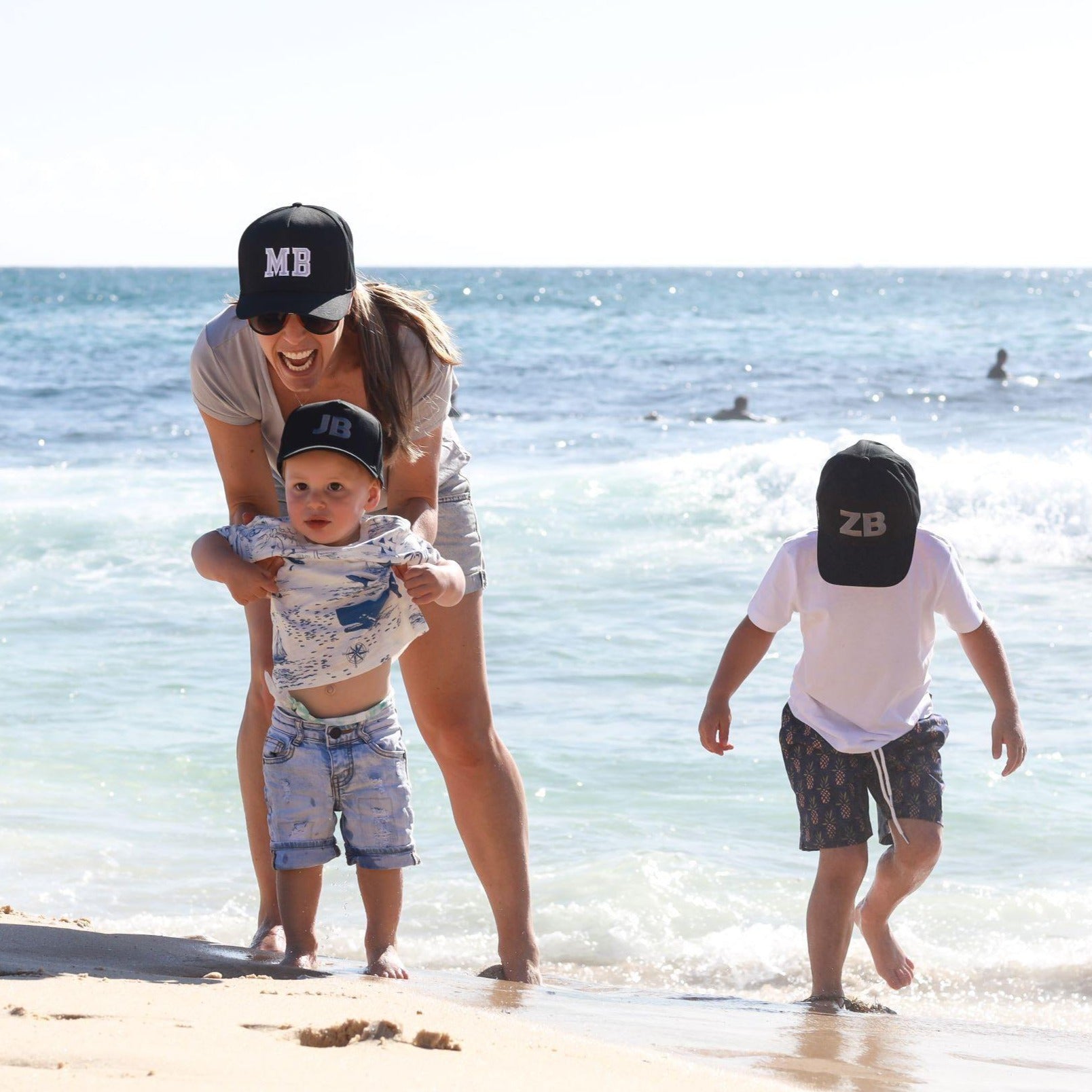 Mum and sons wearing matching personalised black baseball caps with their initials. Cubs & Co. Australia.