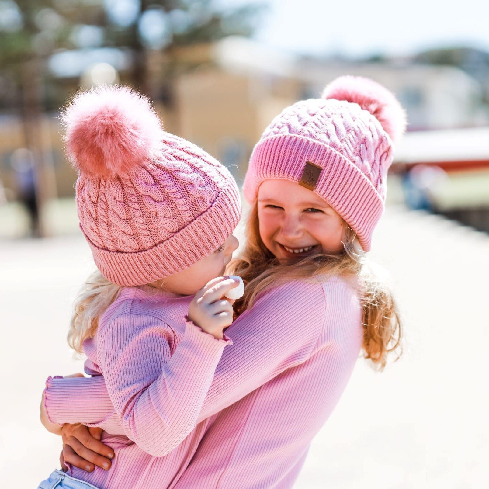 Sisters wearing matching pink winter beanies. Cubs and Co. Australia